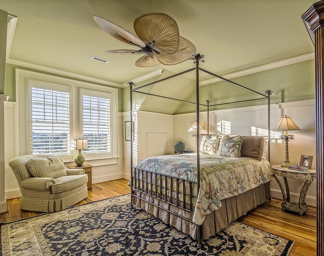 Bedroom interior with a bed against a solid wall, windows to the side, and clear walking space around the bed